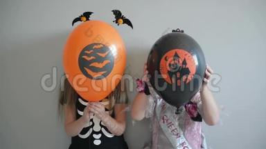 两个微笑的小女孩穿着万圣节服装，拿着气球和摆姿势。